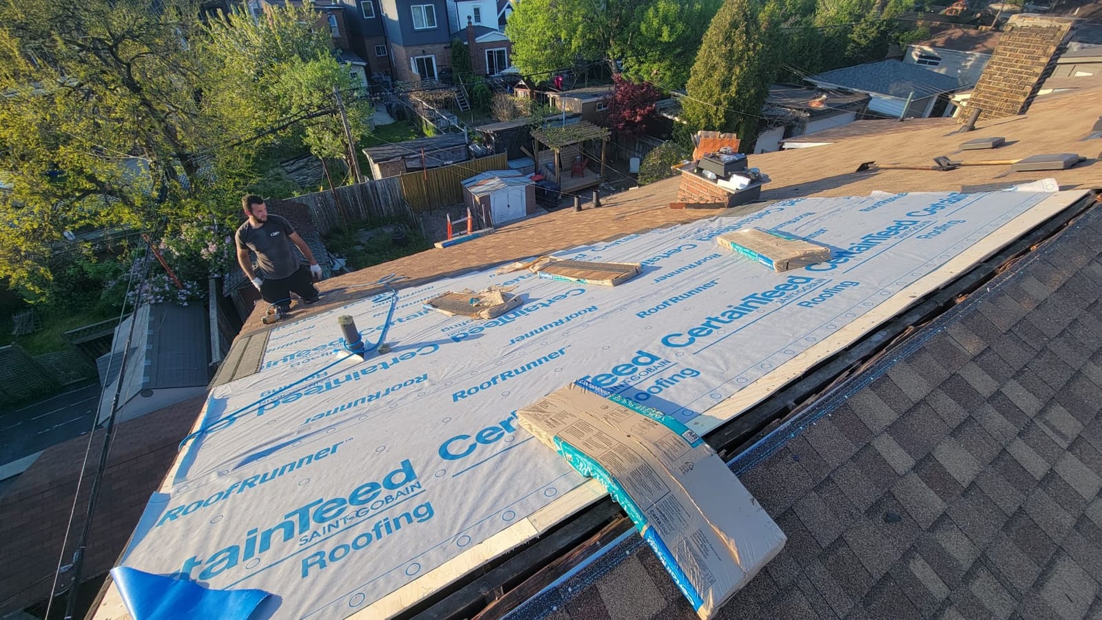 Comfort Roofing crew re-decking a roof with fresh underlayment above an Etobicoke backyard
